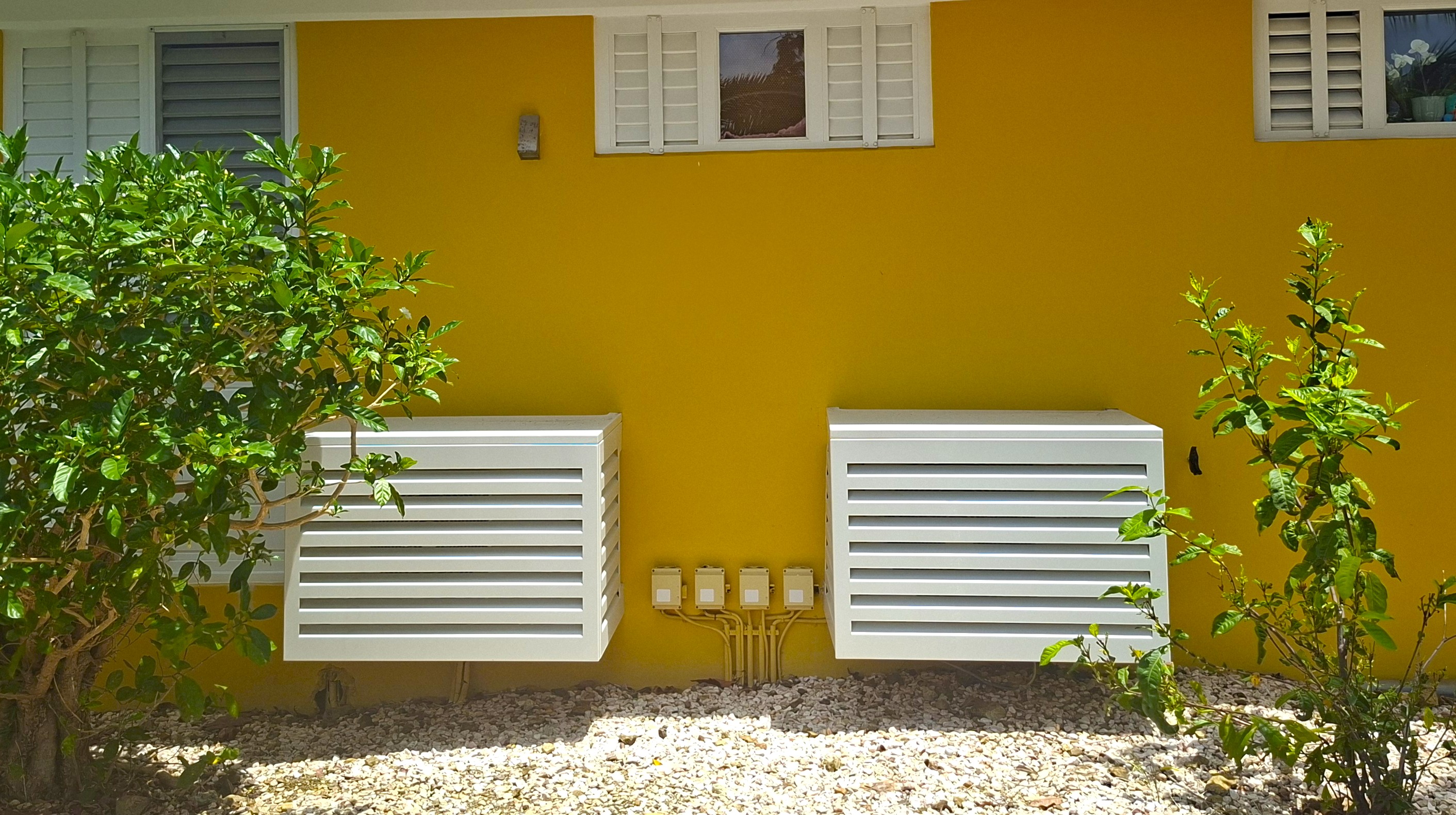 UnderCovers aluminum covers fitted to a yellow house exterior in Curacao