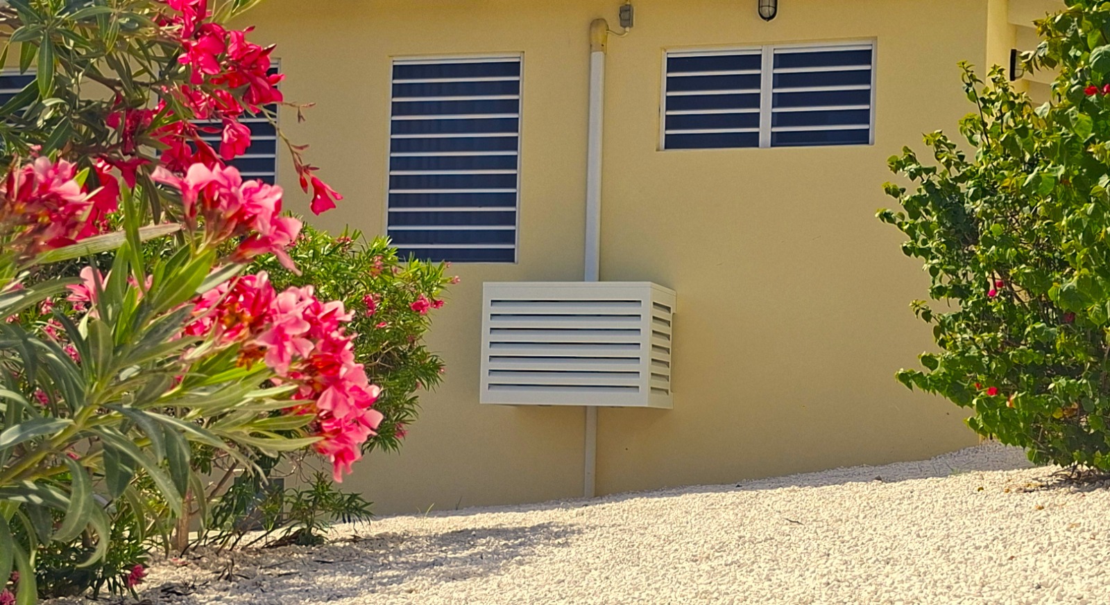 UnderCovers aluminum AC cover blending into a Curacao home exterior