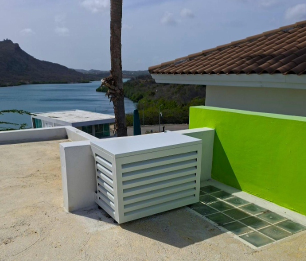 Aluminum airco cover on a coastal terrace beside a lime green wall, overlooking a bay in Curacao